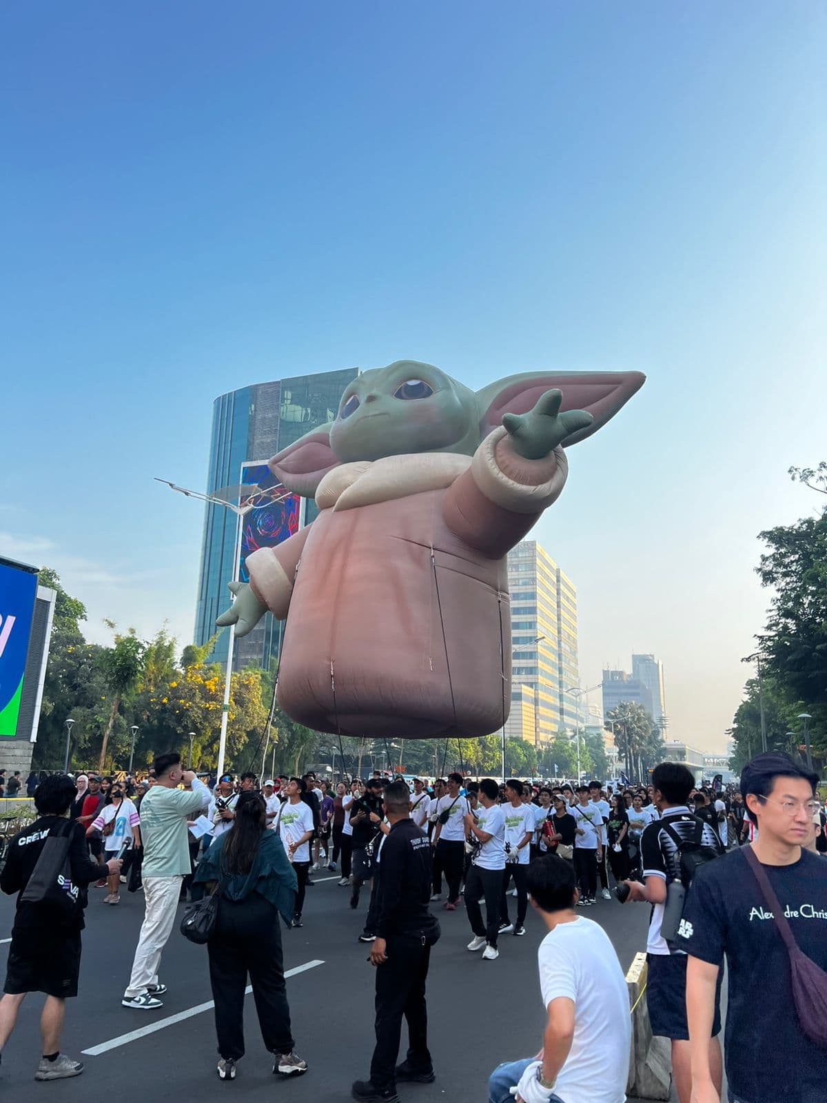 Inflatable helium Grogu berukuran besar mengambang di atas kerumunan pawai jalanan, dibuat untuk Disney Indonesia