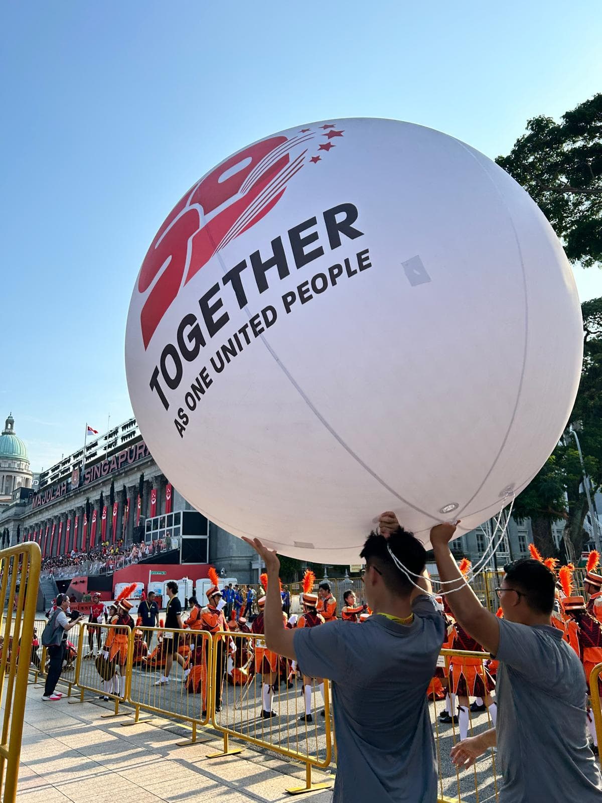 Bola SG59 raksasa bertuliskan Together as One United People, dibawa kru di Parade Hari Nasional Singapura