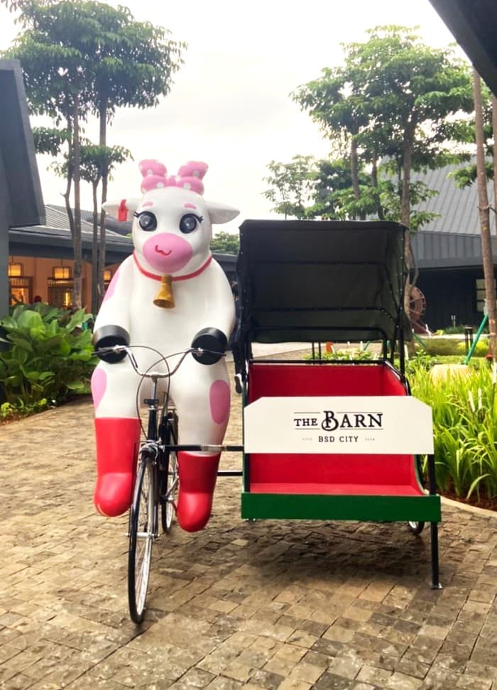 Patung sapi merah muda dan putih mengendarai becak di depan The Barn, BSD City, Indonesia